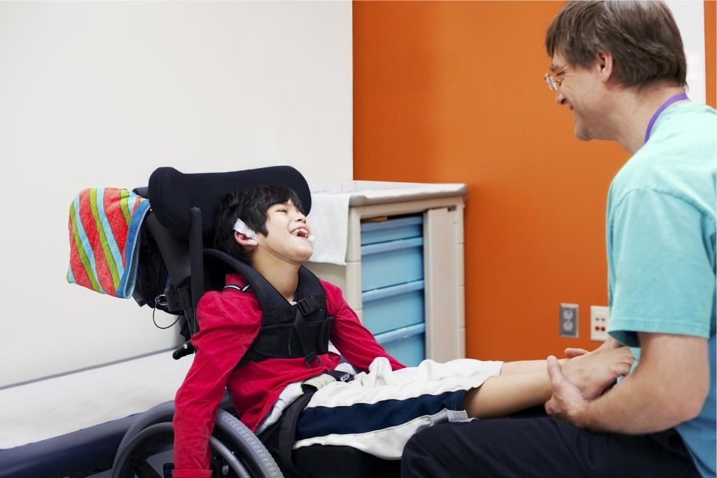 Disabled child in wheelchair being cared for by a special needs therapist